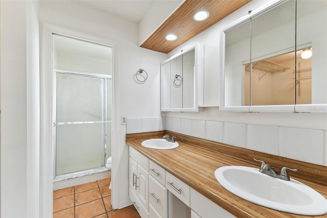 bathroom with decorative backsplash, tile patterned flooring, vanity, an enclosed shower, and toilet