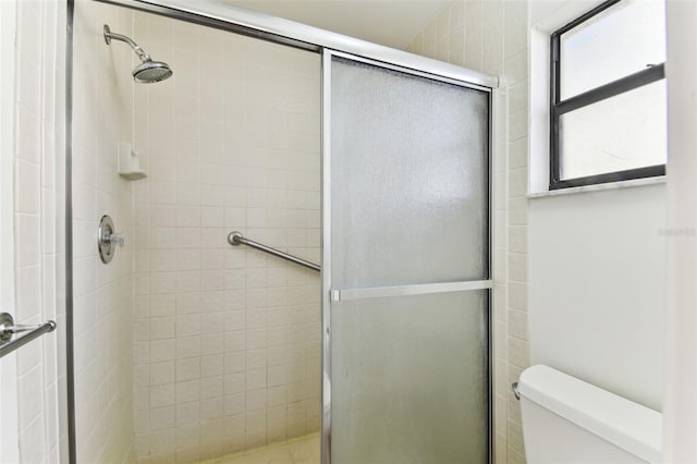 bathroom with a shower with door and toilet