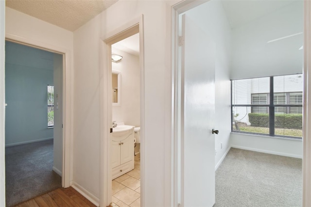 hall with light carpet and a textured ceiling