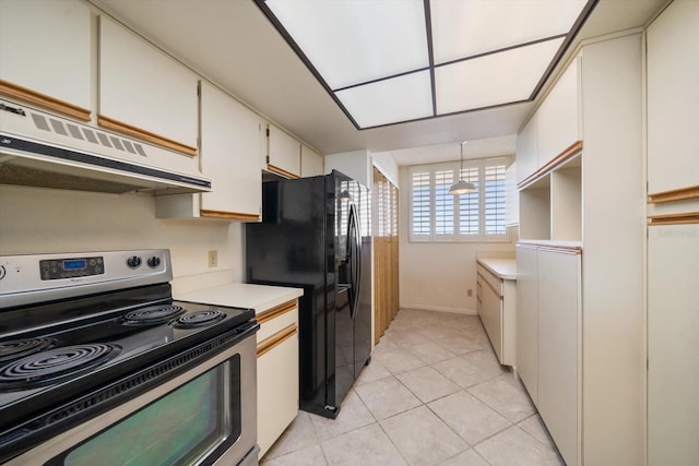 kitchen with decorative light fixtures, white cabinets, light tile patterned floors, black fridge, and stainless steel electric range