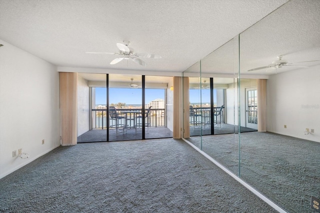 spare room with expansive windows, carpet flooring, a textured ceiling, and ceiling fan