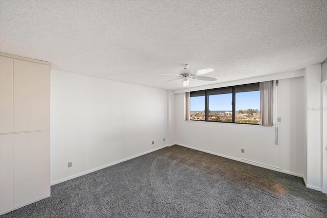 spare room with dark colored carpet, a textured ceiling, and ceiling fan