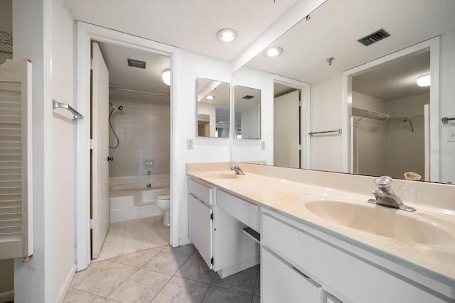 full bathroom with tiled shower / bath, vanity, toilet, tile patterned floors, and a textured ceiling