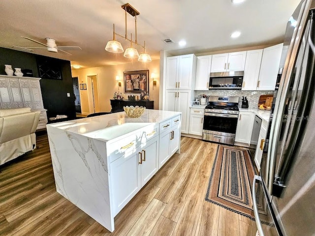 kitchen with white cabinetry, pendant lighting, a center island, and appliances with stainless steel finishes