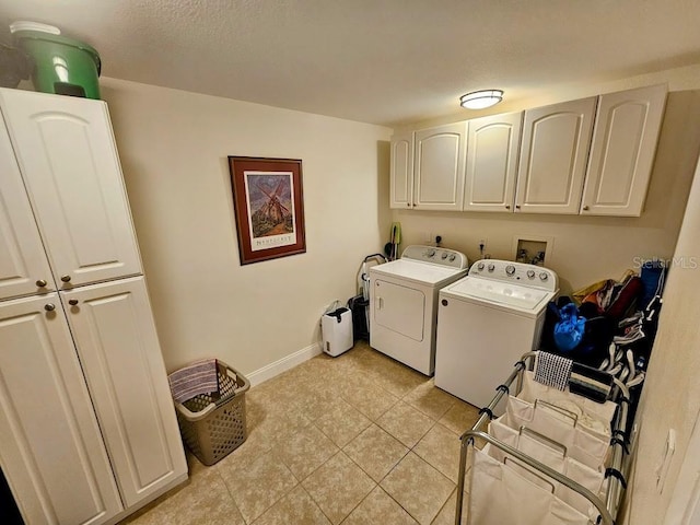 washroom featuring cabinets, light tile patterned floors, washing machine and clothes dryer, and a textured ceiling