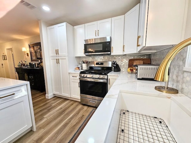 kitchen with white cabinetry, stainless steel appliances, and tasteful backsplash