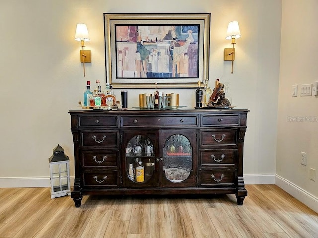 bar featuring dark brown cabinets and light hardwood / wood-style flooring