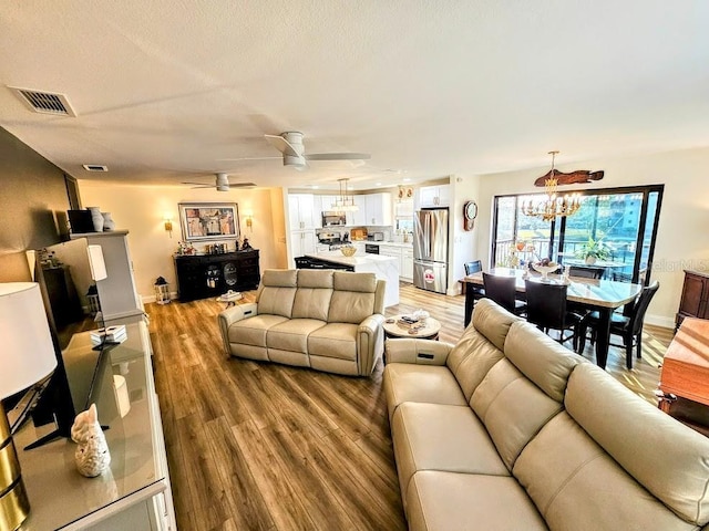 living room featuring ceiling fan with notable chandelier and hardwood / wood-style floors