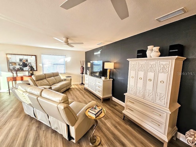 living room featuring ceiling fan, a textured ceiling, and light hardwood / wood-style floors