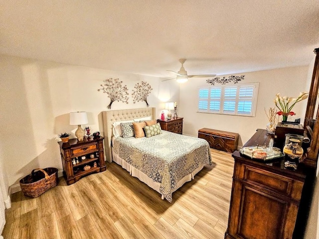 bedroom featuring ceiling fan, light hardwood / wood-style floors, and a textured ceiling