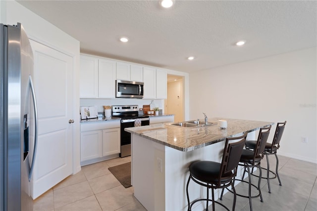 kitchen featuring sink, a breakfast bar area, a kitchen island with sink, stainless steel appliances, and white cabinets