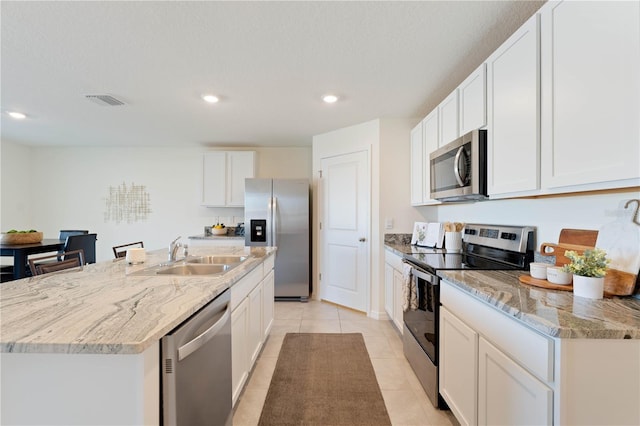 kitchen with white cabinetry, sink, a kitchen island with sink, light tile patterned floors, and stainless steel appliances