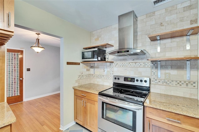 kitchen featuring wall chimney exhaust hood, pendant lighting, stainless steel appliances, light stone countertops, and decorative backsplash