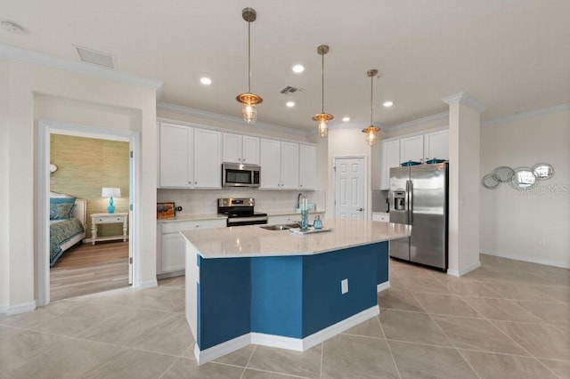 kitchen with sink, appliances with stainless steel finishes, an island with sink, pendant lighting, and white cabinets