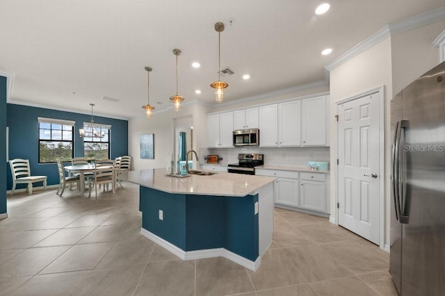 kitchen with a kitchen island with sink, hanging light fixtures, backsplash, stainless steel appliances, and white cabinets