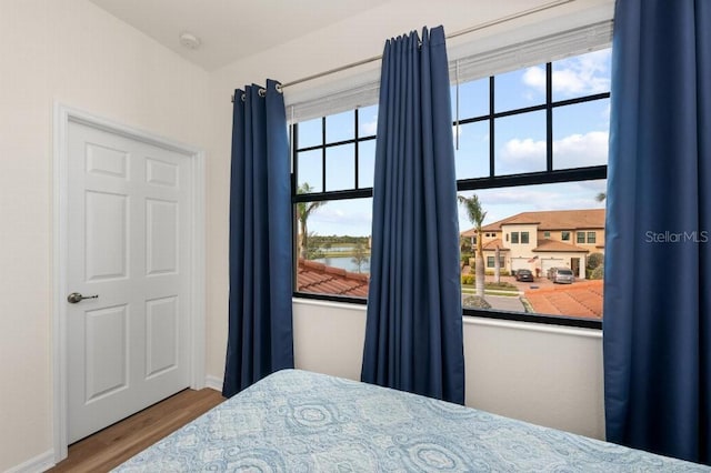 bedroom featuring a water view, hardwood / wood-style floors, and multiple windows