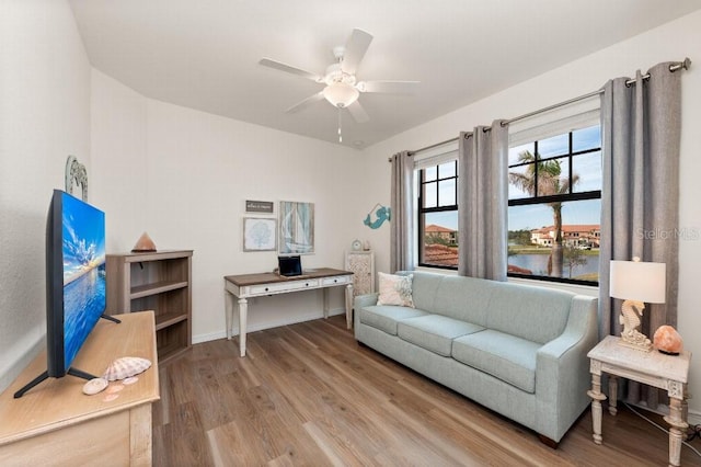 living room featuring wood-type flooring, a water view, and ceiling fan