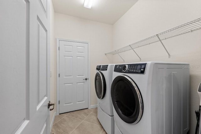 clothes washing area featuring light tile patterned floors and washing machine and clothes dryer