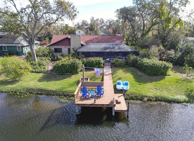 view of dock with glass enclosure, a yard, and a water view