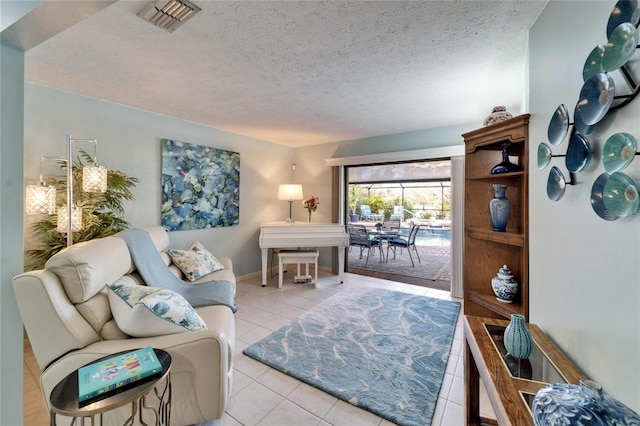 living area featuring light tile patterned flooring, visible vents, a textured ceiling, and baseboards