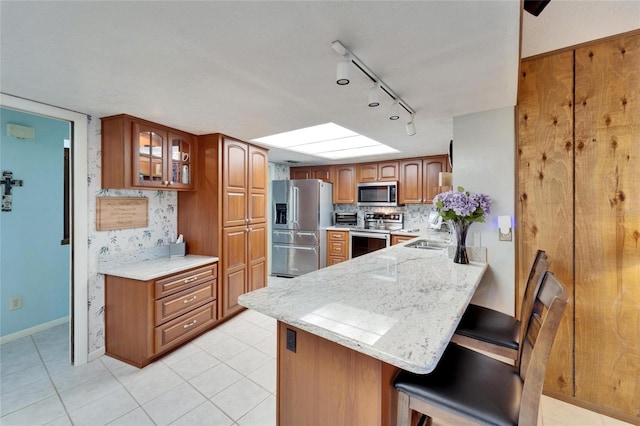 kitchen featuring tasteful backsplash, sink, a breakfast bar area, kitchen peninsula, and stainless steel appliances