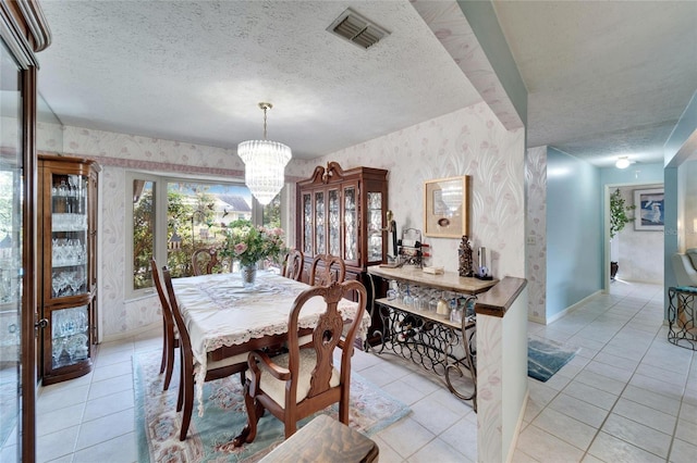 dining room featuring wallpapered walls, visible vents, and a textured ceiling