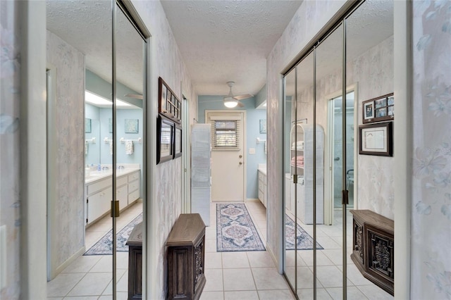 corridor with light tile patterned floors, plenty of natural light, and a textured ceiling