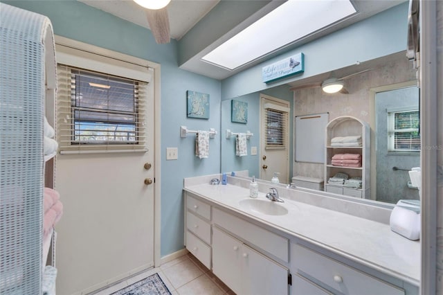 bathroom featuring tile patterned flooring, a skylight, vanity, and baseboards