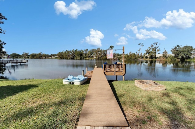 view of dock with a water view and a yard