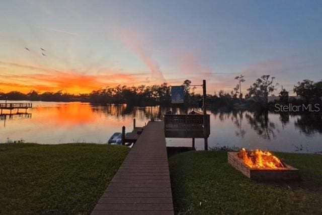 view of dock with a yard, a water view, and an outdoor fire pit