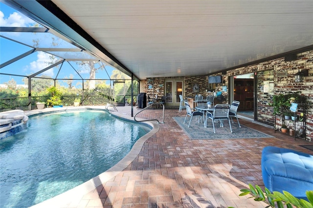 view of pool with a lanai, french doors, a pool with connected hot tub, and a patio