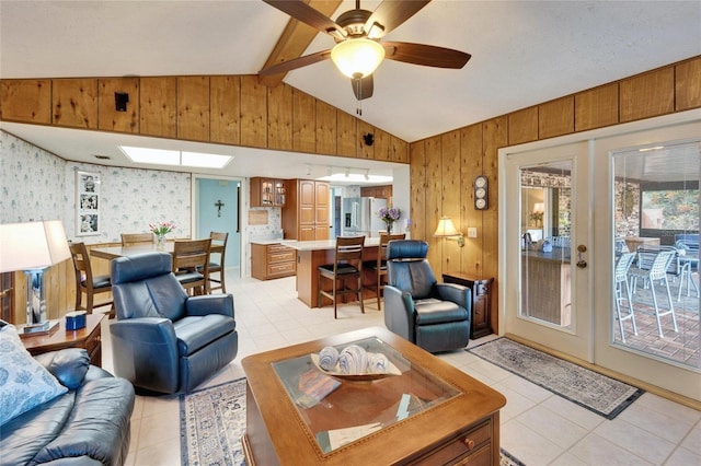 living area featuring light tile patterned floors, vaulted ceiling with beams, french doors, and wood walls