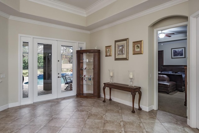 doorway featuring a raised ceiling, ornamental molding, ceiling fan, and french doors