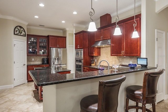 kitchen with hanging light fixtures, decorative backsplash, a breakfast bar, and appliances with stainless steel finishes