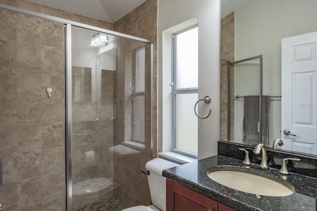 bathroom with vanity, a shower with door, and toilet