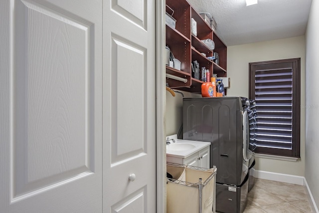 laundry room with sink, a textured ceiling, washing machine and clothes dryer, and light tile patterned flooring