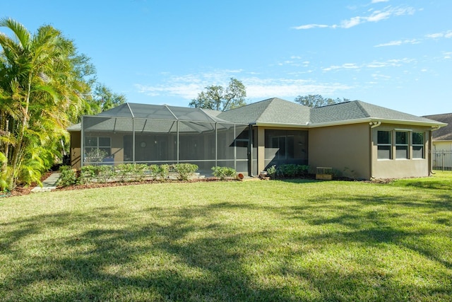 rear view of property with a lanai and a lawn