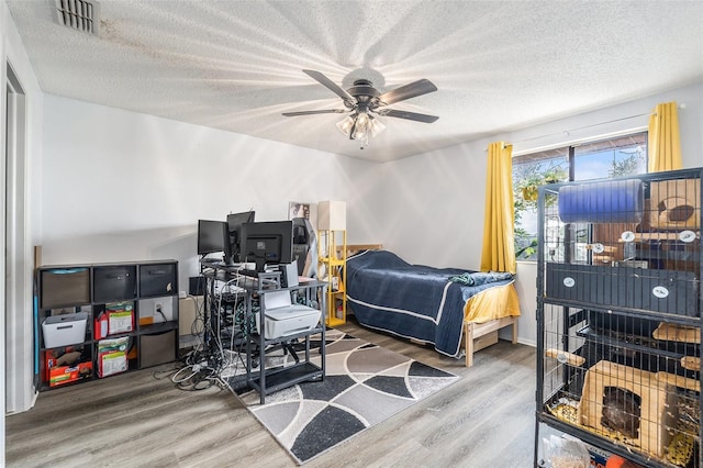 bedroom featuring ceiling fan, wood-type flooring, and a textured ceiling