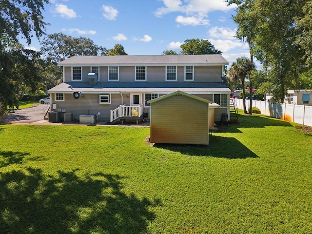 rear view of property featuring central AC unit and a lawn