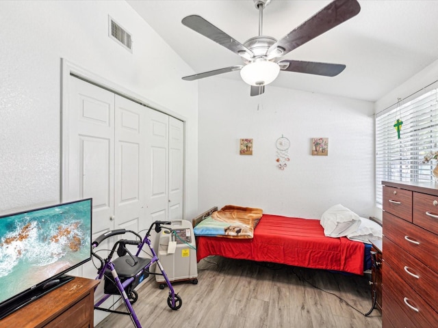 bedroom with ceiling fan, vaulted ceiling, a closet, and light hardwood / wood-style flooring