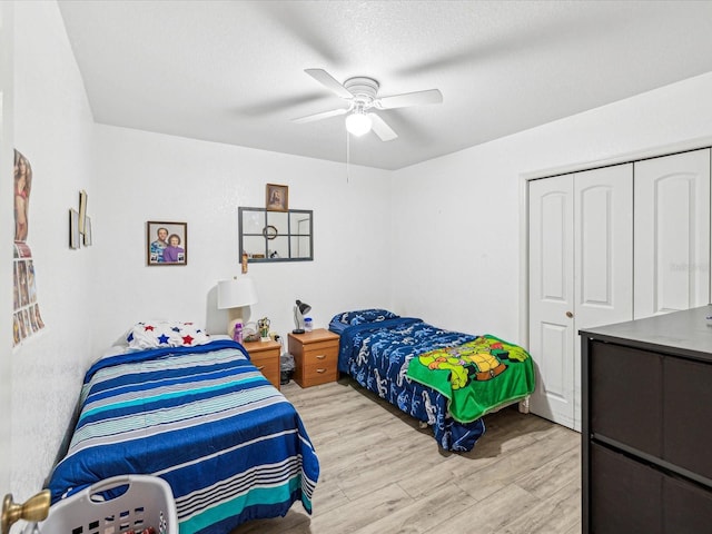 bedroom with a textured ceiling, light hardwood / wood-style flooring, a closet, and ceiling fan