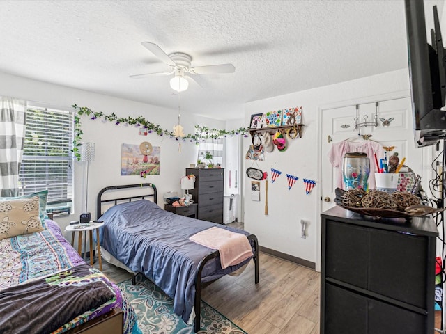 bedroom with ceiling fan, a textured ceiling, and light wood-type flooring