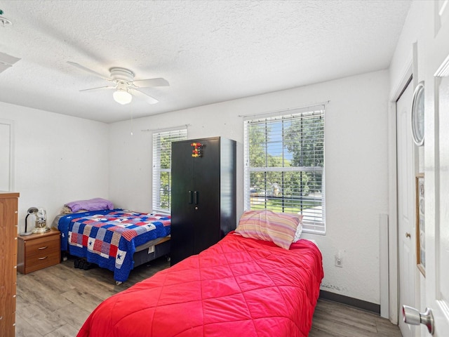 bedroom with ceiling fan, wood-type flooring, and a textured ceiling