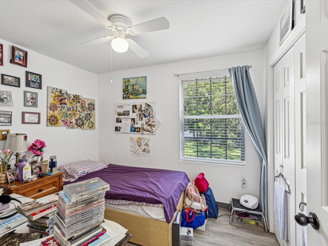 bedroom with light hardwood / wood-style flooring, a textured ceiling, ceiling fan, and a closet