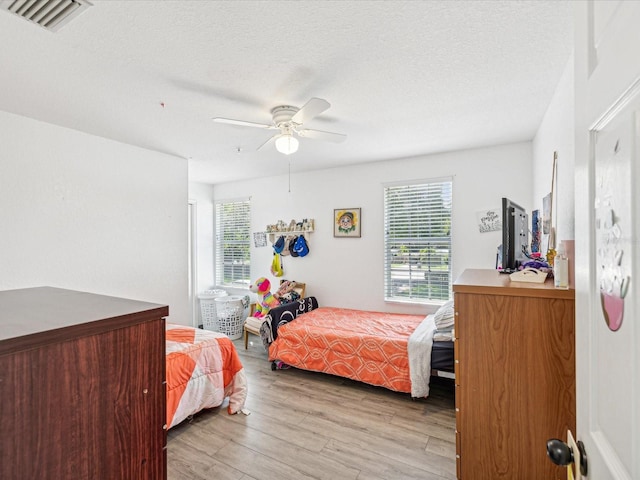 bedroom with multiple windows, ceiling fan, a textured ceiling, and light wood-type flooring