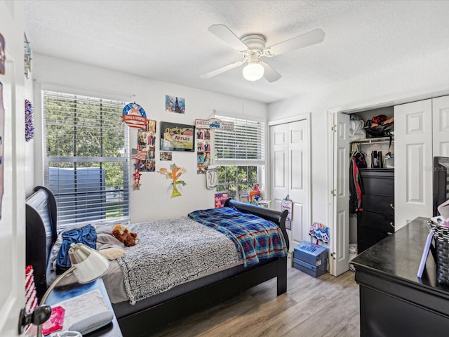 bedroom featuring multiple windows, a textured ceiling, ceiling fan, and light wood-type flooring