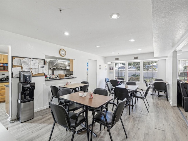 dining space with a textured ceiling and light wood-type flooring