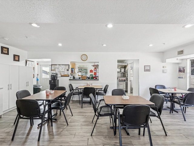 dining area featuring light hardwood / wood-style floors and a textured ceiling