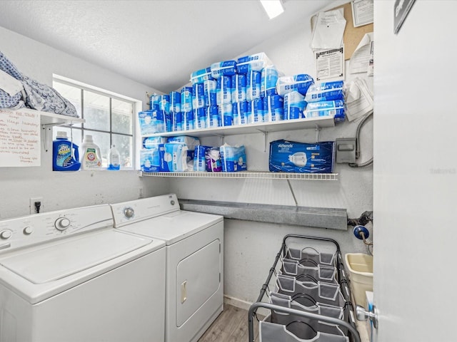 clothes washing area featuring wood-type flooring, separate washer and dryer, and a textured ceiling