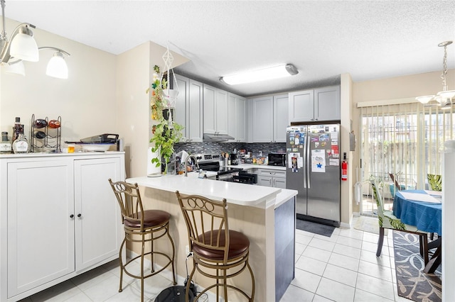 kitchen with pendant lighting, stainless steel appliances, kitchen peninsula, and gray cabinetry